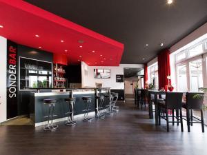 德累斯顿德累斯顿机场DORMERO酒店 的餐厅设有酒吧凳和红色天花板