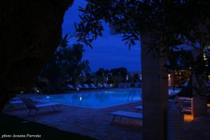 托雷坎内马塞里亚托雷德迪亚曼特乡村民宿的游泳池在晚上,周围设有两把长椅
