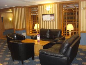 伯恩茅斯卡林顿房屋酒店的客厅配有皮革家具和桌椅