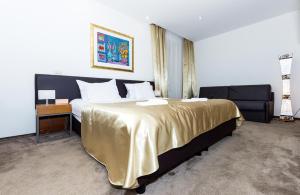 斯普利特玛儒林酒店的一间卧室配有一张带金色毯子的大床