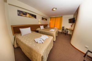 库斯科Hotel De la Villa Hermoza的酒店客房设有两张床和电视。
