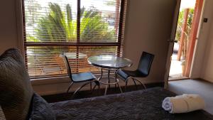 布罗肯希尔Gateway Motor Inn - Self Check-In的客房设有一张床、一张桌子、椅子和一扇窗户。