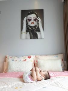 华欣所皮达特露斯特华公寓的躺在床上的婴儿,上面有一张女人的照片