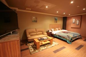 龟山萨瑞赛奇国际店（仅限成人）的一间卧室配有一张床、一张沙发和一张桌子