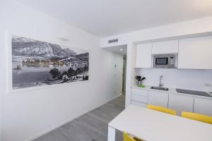 托尔博莱Bertamini Apartments的厨房配有白色橱柜,墙上挂有绘画作品