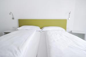 托尔博莱Bertamini Apartments的一张带白色床单和绿色床头板的床