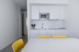 托尔博莱Bertamini Apartments的白色的厨房配有2把黄色椅子和水槽