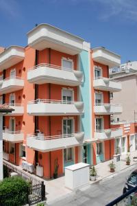 里米尼奥林波公寓式酒店的一座橙色的建筑,在街上设有白色阳台
