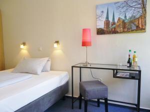 吕贝克姆勒特赫酒店的一间卧室配有一张床和一张带台灯的书桌