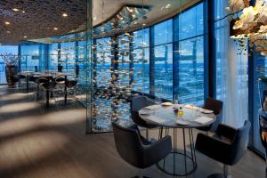 阿姆斯特丹阿姆斯特丹弗莱彻酒店的餐厅设有桌椅和大窗户。