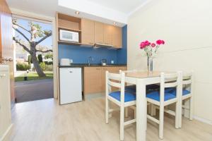 波连萨港弗洛拉公寓酒店的一间带桌椅的厨房和一间带蓝色墙壁的厨房