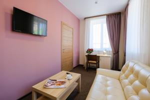 托木斯克Hotel Galereya的客厅配有沙发和粉红色墙壁上的电视