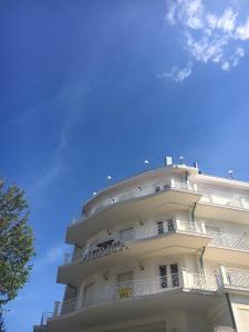里米尼御夫座酒店的一座高大的白色建筑,背后是蓝天