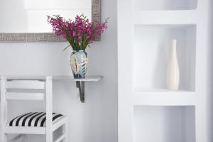 纳乌萨滨海简易别墅的花瓶,花瓶上布满紫色的花,桌子上布满椅子