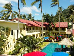芭东海滩Austrian Garden Hotel & Restaurant Patong的一个带游泳池、棕榈树和遮阳伞的度假村