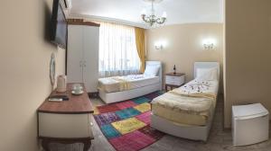安塔利亚Ozmen Hotel的一间卧室配有两张床、一张桌子和一台电视。