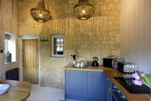 莫顿因马什沃尔纳特度假屋的厨房配有蓝色橱柜和石墙