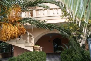 圣伊西多罗Villa Salentina的一座有拱门和棕榈树的建筑