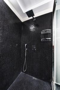 伊亚埃利亚度假村 - 仅限成人 的带淋浴的浴室和黑色瓷砖墙壁