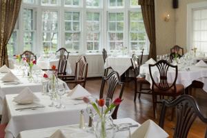 本宁顿弗齐米丽宾馆的餐厅设有白色的桌椅和窗户。