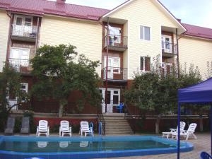 乔尔蓬阿塔Mini-pansionat Maksat的一座带白色椅子的建筑前的游泳池