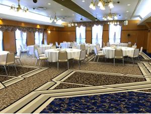 佐野市太阳道佐诺酒店 的宴会厅配有白色的桌椅