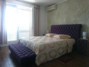 波尔托罗Guest House Vila Luka的一间卧室配有一张大床和紫色的簇绒床架