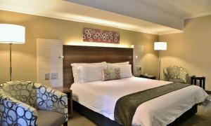 博克斯堡伯奇伍德酒店及OR坦博会议中心的一间卧室配有一张大床和两把椅子