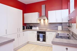 约克3 The Kings的厨房配有白色橱柜和红色墙壁
