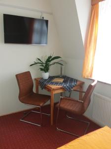 德累斯顿罗西维兹酒店的一间配备有桌子和两把椅子及一台电视的房间