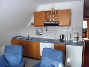 内贝尔Gästehaus Kapitän Jan Ricklefs的厨房配有水槽和2把蓝色椅子