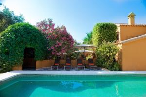 EsteponaFamily hotel Al- Ana Marbella的一座带椅子和遮阳伞的别墅前的游泳池