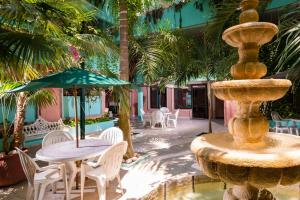 卡门城Hotel Acuario的喷泉配有椅子和桌子及雨伞