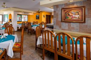 卡门城Hotel Acuario的餐厅设有桌椅,墙上挂有绘画作品