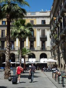 巴塞罗那罗马雷阿尔酒店的带着行李走在街上的男人和女人
