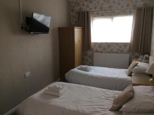 格兰瑟姆The Avenue Hotel的酒店客房设有两张床和一台墙上的电视。