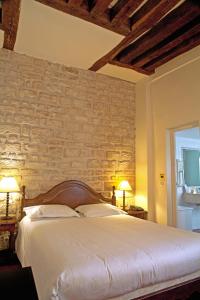 巴黎多尼克卢浮宫酒店的一间卧室设有一张带砖墙的大床