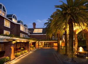 门洛帕克The Stanford Park Hotel的一座楼前种有棕榈树的庭院