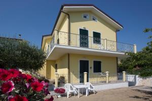 努马纳Giglio Del Conero的黄色房屋 - 带两把白色椅子和阳台
