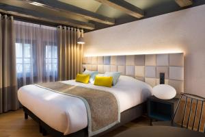 科尔马Hotel Le Colombier Suites的卧室配有一张带黄色枕头的大型白色床。