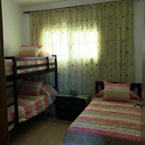 卡博尼格洛Appartement Bellavista - Cabo Negro的一间卧室设有两张双层床和一扇窗户。
