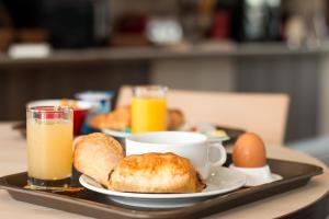 谢尔河畔阿瑟ACE Hôtel Travel Athée sur Cher的托盘,包括早餐食品和桌上的饮料