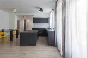 福纽德Vitorlás Apartman的厨房配有黑色橱柜、桌子和黄色椅子