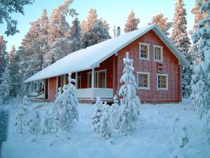 罗瓦涅米利可小木屋的一座红色的房子,前面有一棵雪覆盖的树