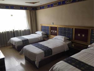 夏河县华侨饭店的酒店客房设有三张床和窗户。