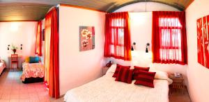 Neve Shalom尼夫沙洛姆酒店的一间设有红色窗帘的卧室和一张位于客房内的床