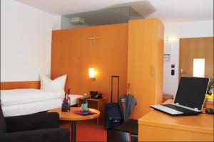 Aschau am Inn登博斯科酒店的一间卧室配有一张床和一张带笔记本电脑的书桌