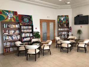 突尼斯Hotel AL KARMEL的图书馆配有桌椅和书架