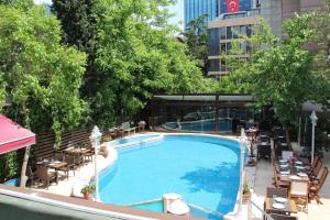 伊斯坦布尔Villa Blanche Hotel SPA & Garden Pool的大楼旁的大型游泳池配有桌椅