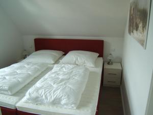 青斯特3-Zi-Ferienwohnung Piratennest 2的一间卧室配有两张带白色床单和红色床头板的床。